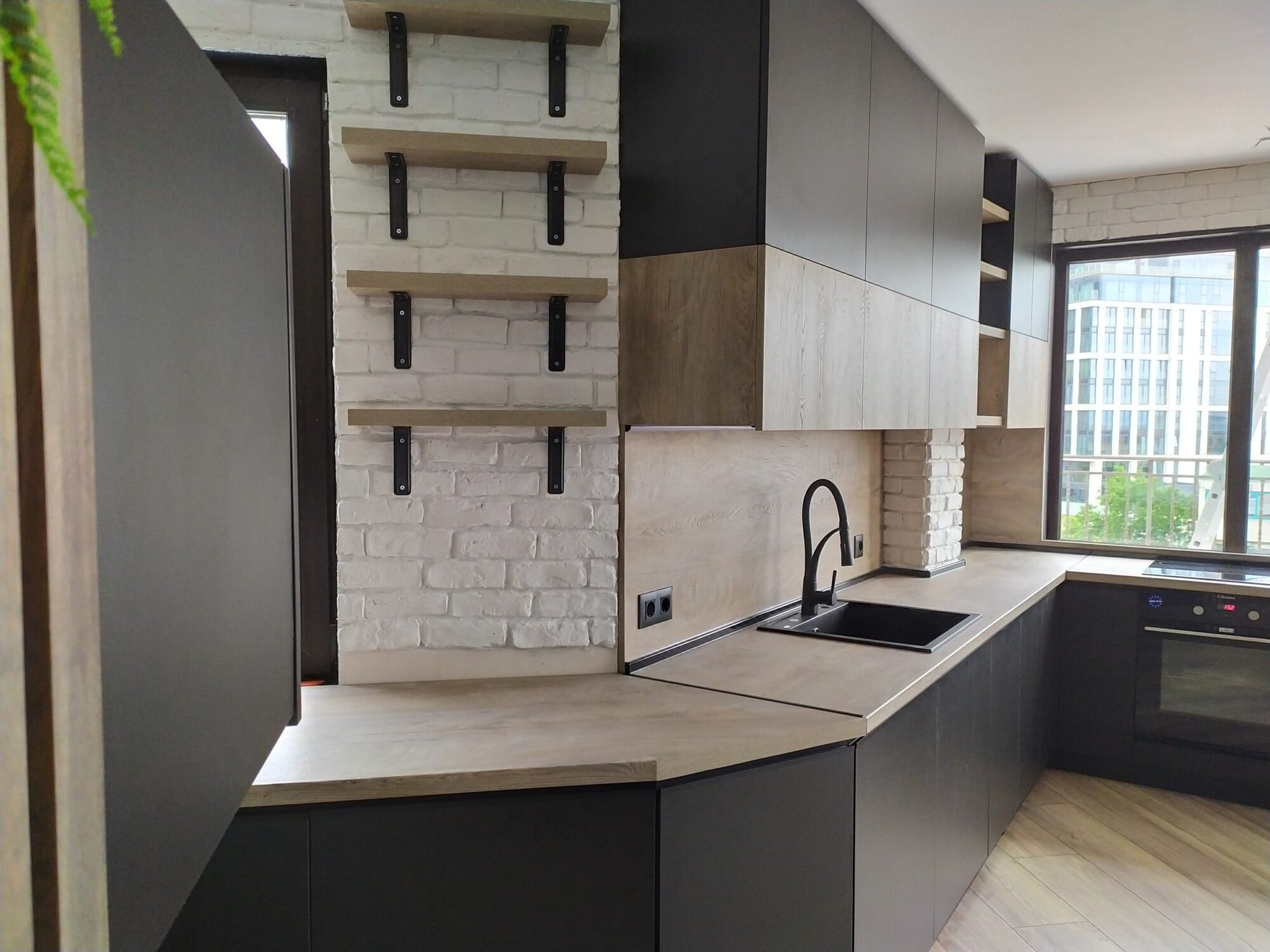 Ъглова композиция с мивка под прозорец, шкафове U899 ST9 EGGER, корпус U999 ST9 EGGER и работен плот K5412 RO Kaindl, подходяща за модерни апартаменти.