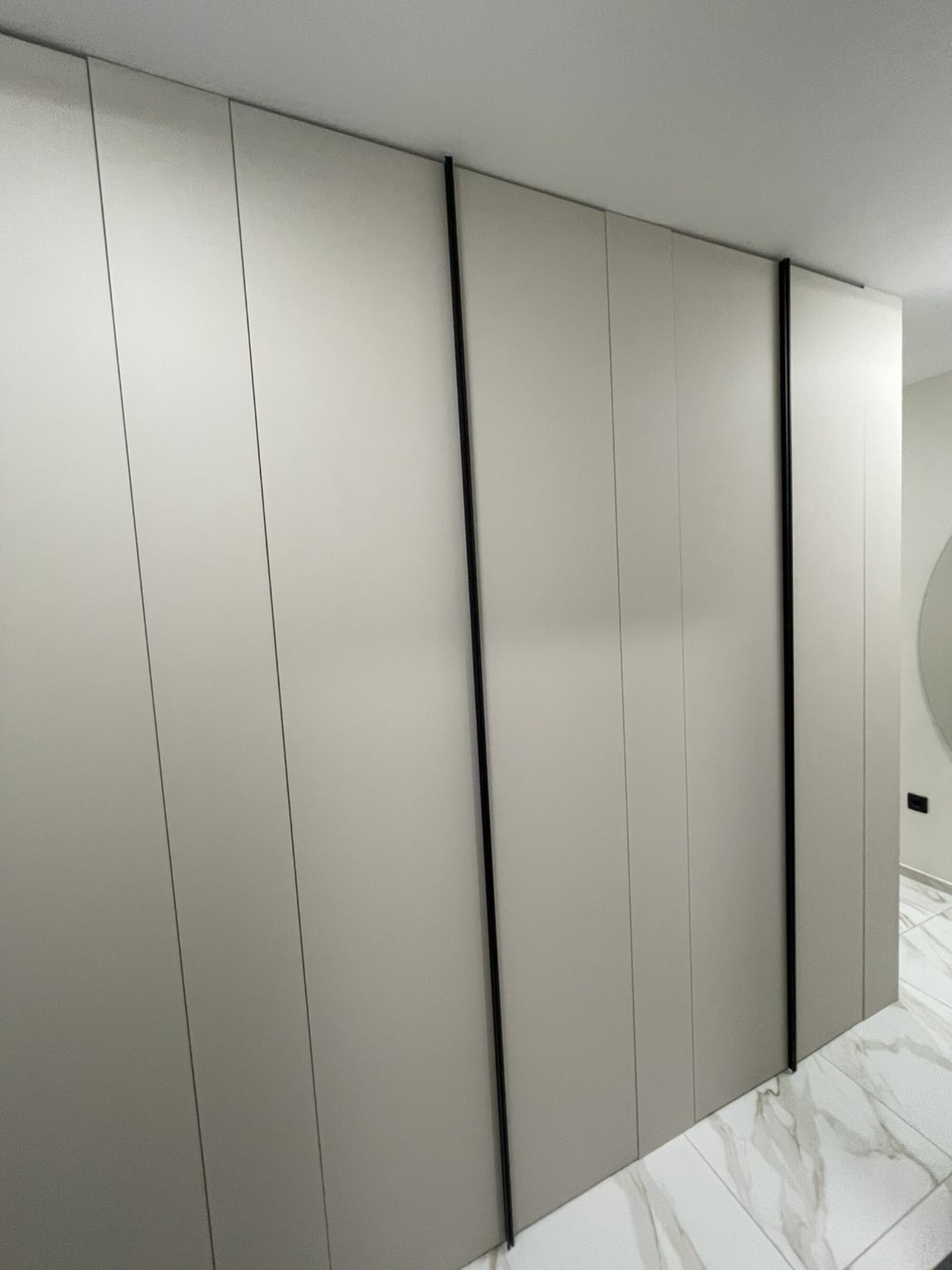 Минималистични врати до таван в кашмирен тон с дискретни вертикални черни акценти.