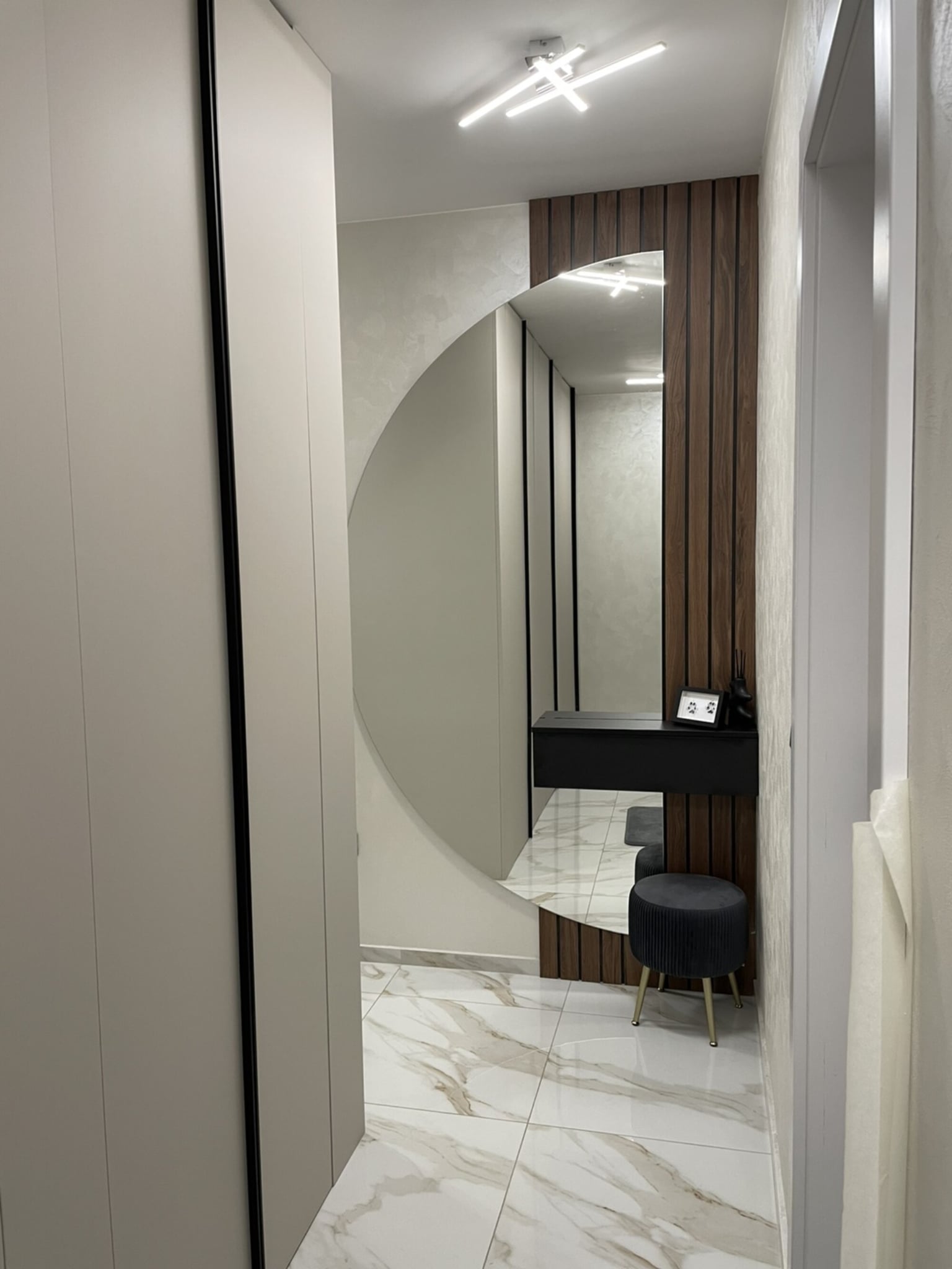 Детайл от огледална композиция с конзолна полица и вертикален дървесен акцент от тъмен дъб.