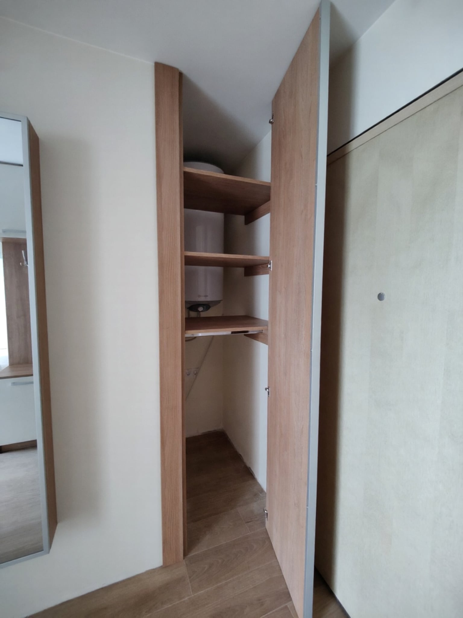 Висок гардероб в коридор с гладки фронтове в цвят Каме и топъл дървесен интериор, проектиран за максимално съхранение