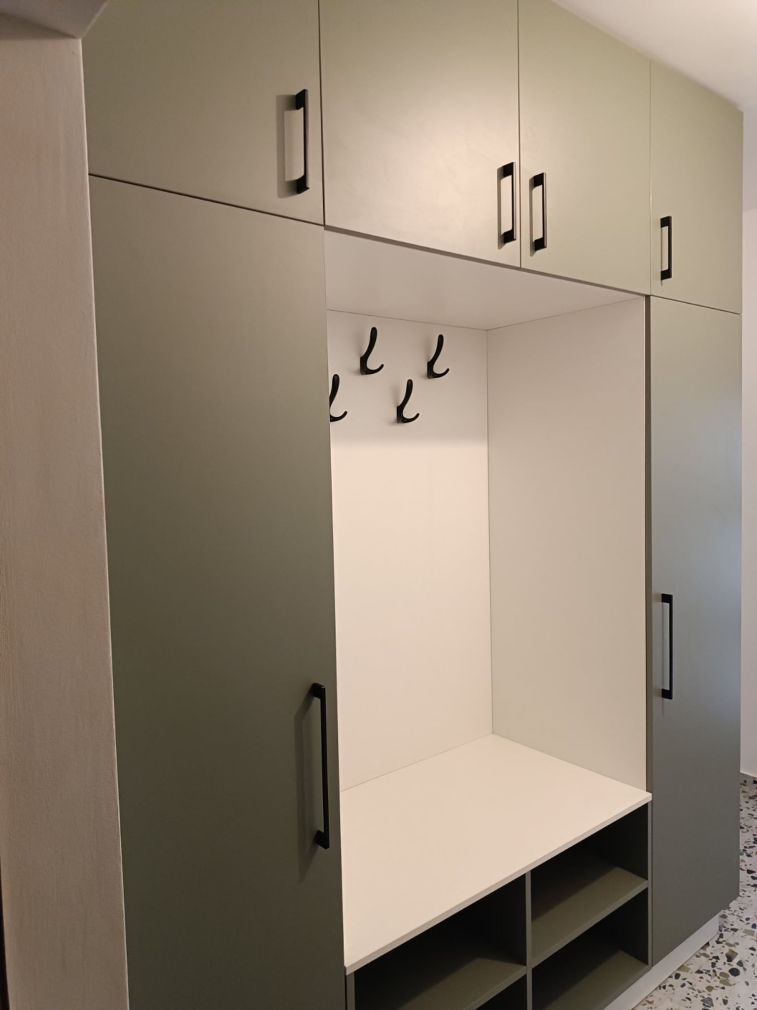 Детайл от вградено място за сядане с отворени ниши за обувки, комбинирано с изчистена бяла повърхност