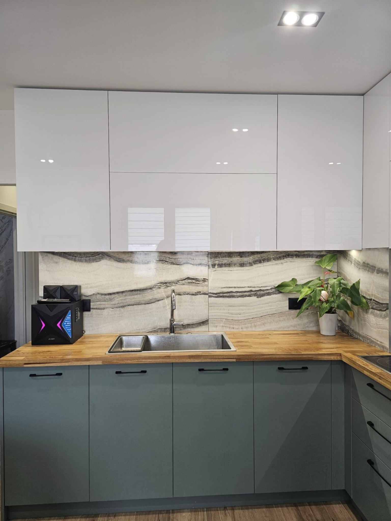 Горен ред гланцови бели врати PerfectSense с плавно затваряне, подредени над плот от масив.