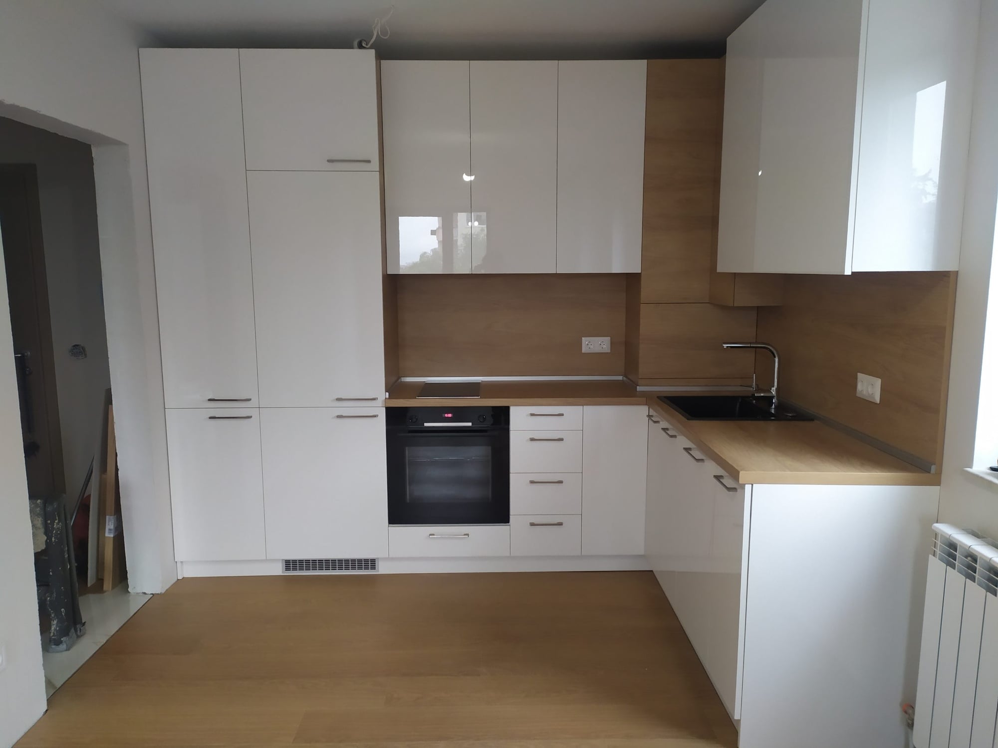 Работна зона с вградена фурна и индукционен плот в непрекъсната дървесна повърхност.