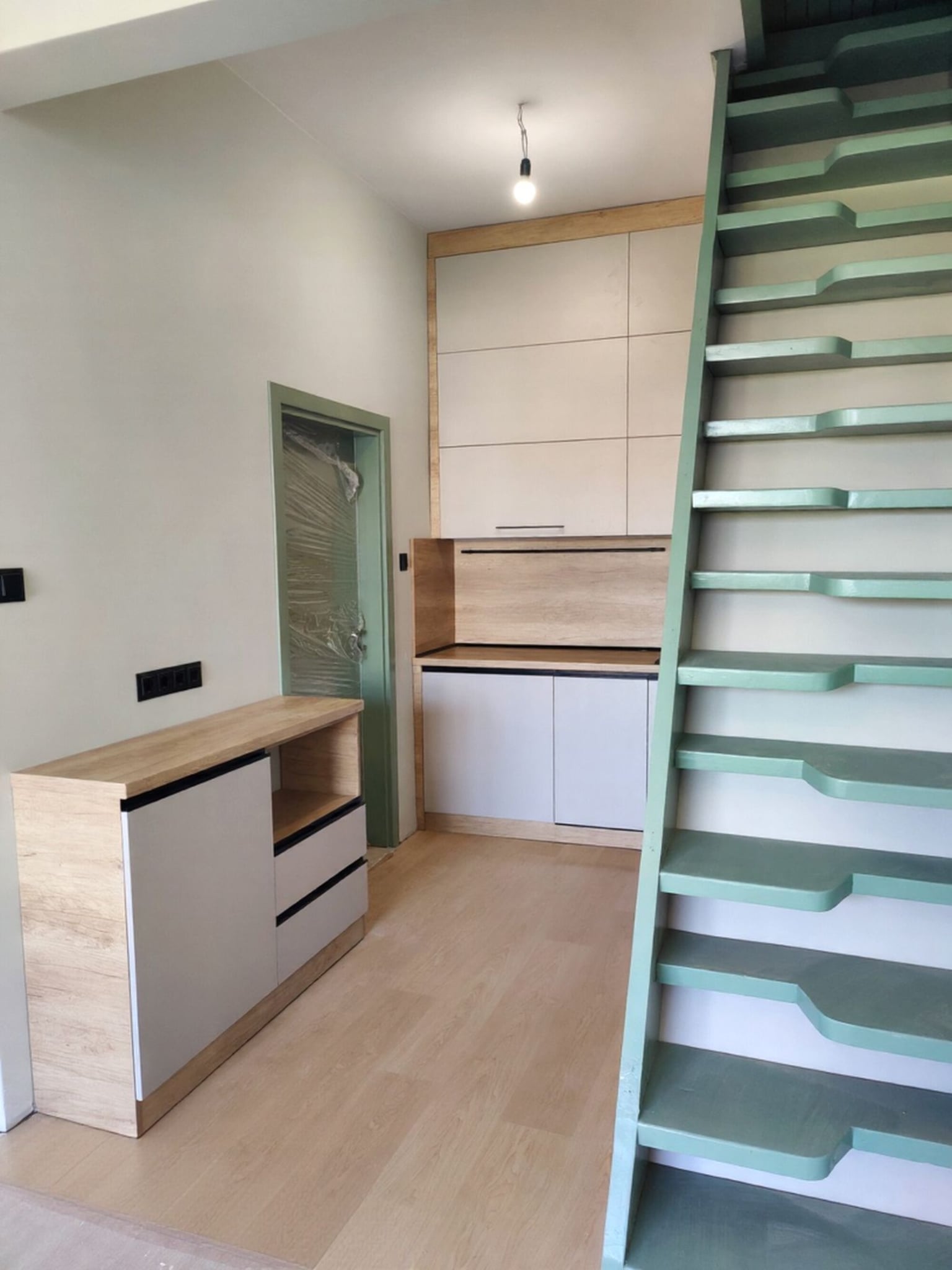 Долен ред шкафове с изчистени кашмирени лица и минималистични черни кант дръжки.