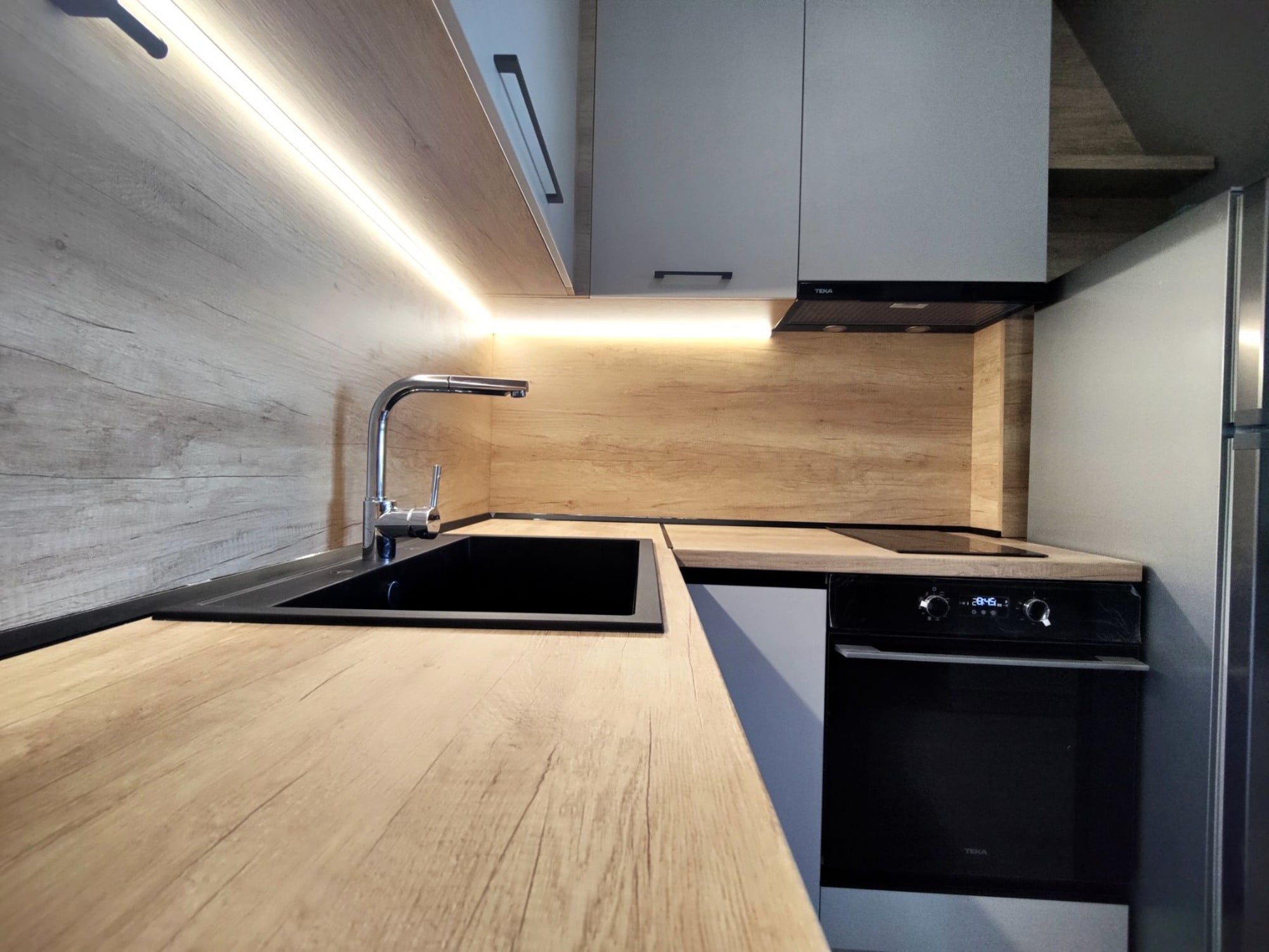 Работна зона с черна мивка FAT и стоящ смесител върху плот в декор Дъб Небраска Натур.