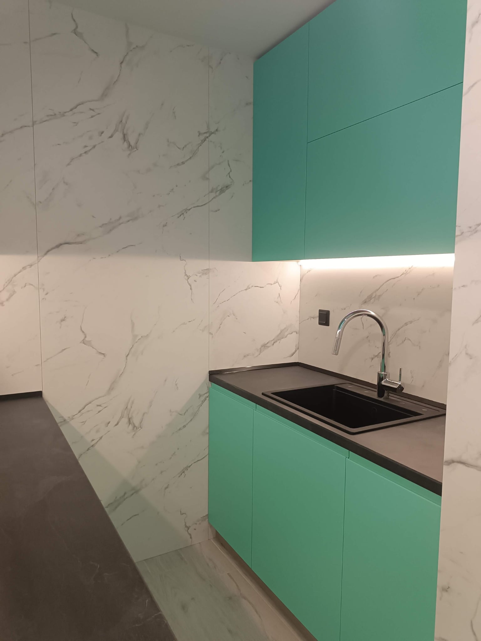 Горни шкафове в свеж тюркоаз с изчистени фуги и скрито осветление под тях.