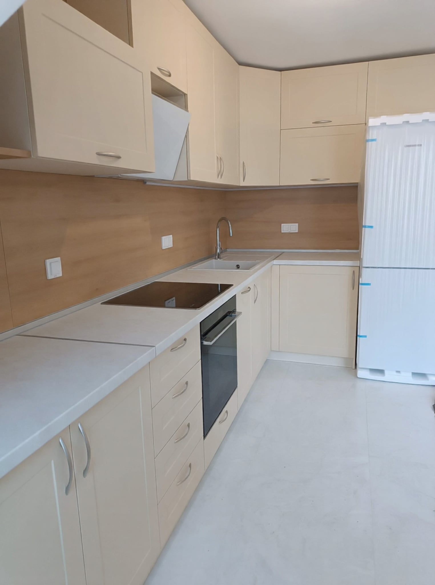 Работна зона със стъклокерамичен плот и вградена фурна в композиция с чекмеджета.