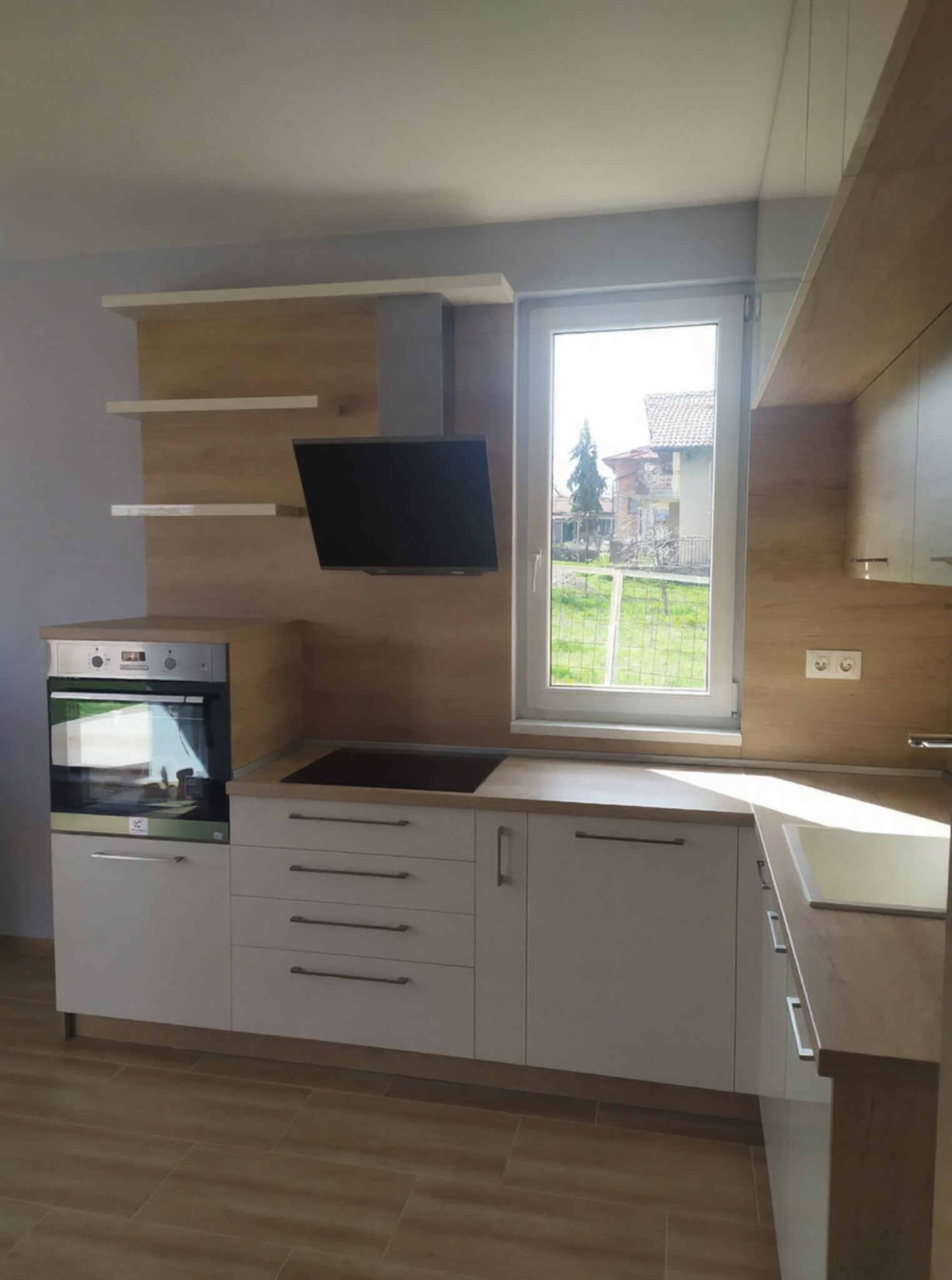 Зона с фурна и котлони под прозореца с дълбоки чекмеджета и плавно затваряне