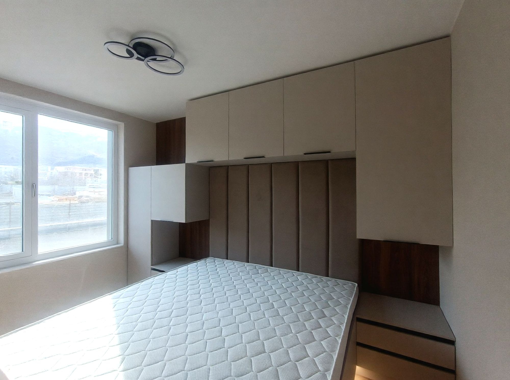 Общ изглед на спалнята с мека табла по цялата ширина и мебелна линия до тавана