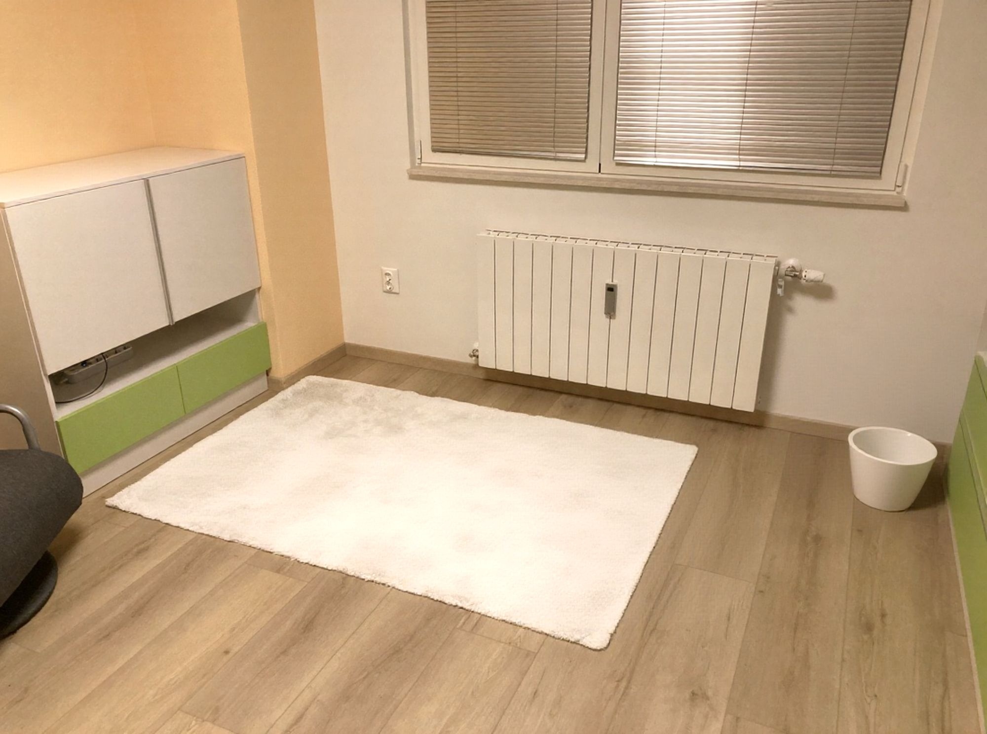 Нисък модул с лайм чекмеджета под прозореца – практично съхранение и цветен акцент в зоната за игра.