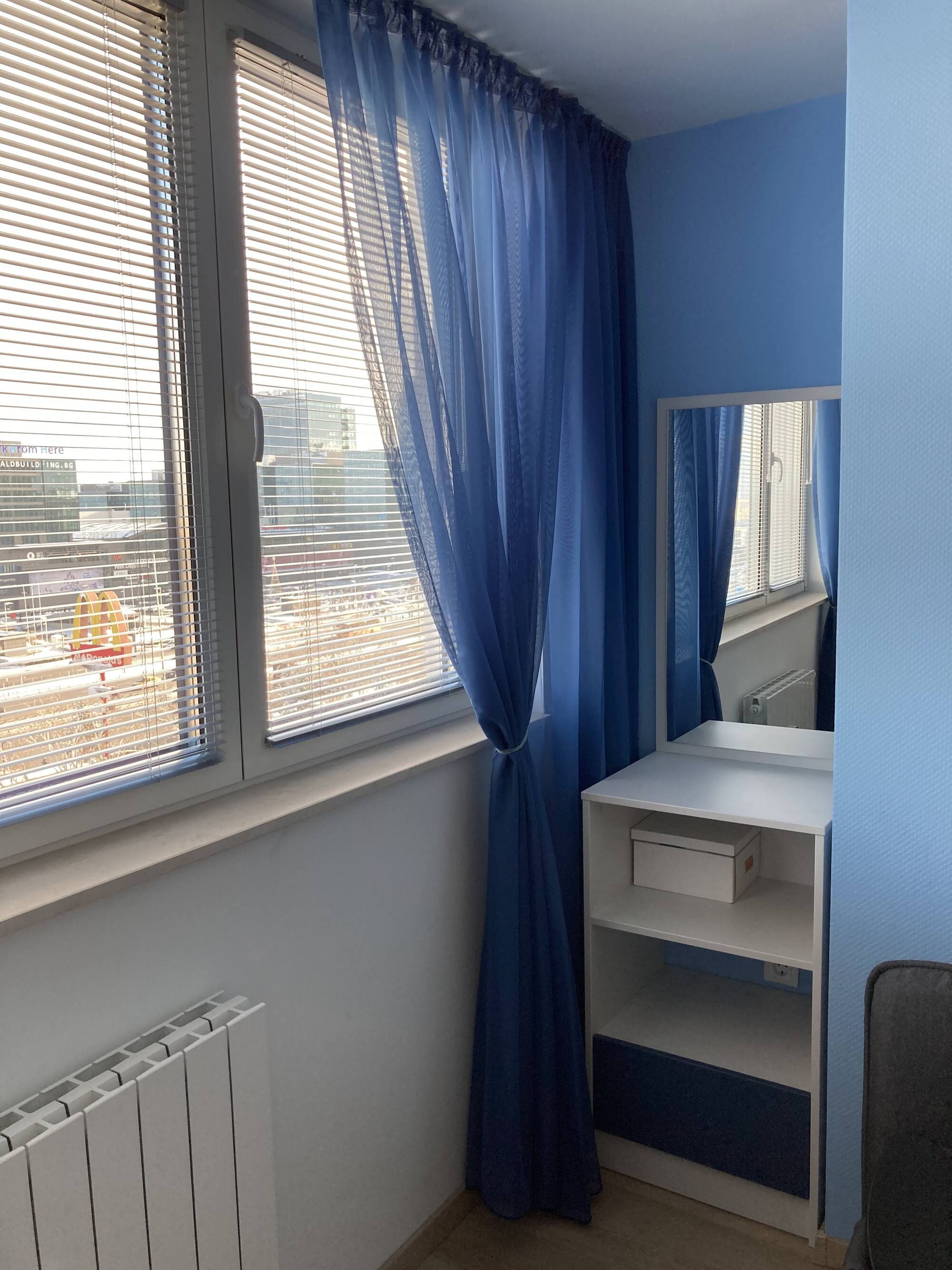 Тоалетка с огледало и отворени ниши, позиционирана в светлата част на стаята