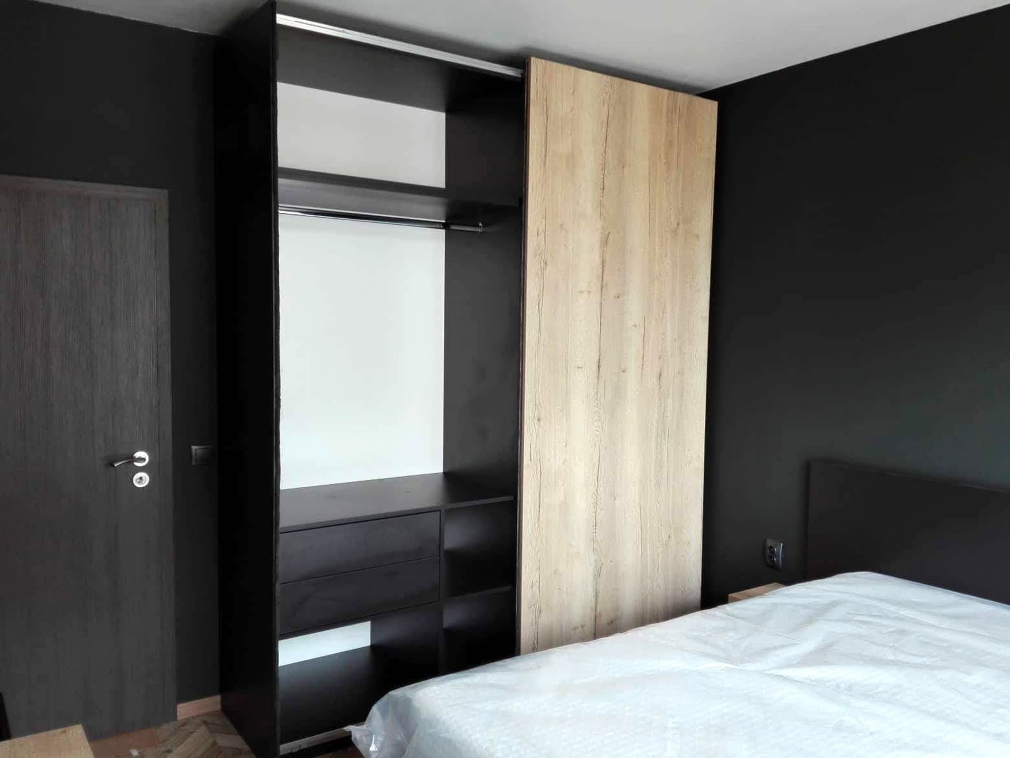 Отворен гардероб с вътрешни чекмеджета и рафтове в контраст между черно и светъл дървесен декор