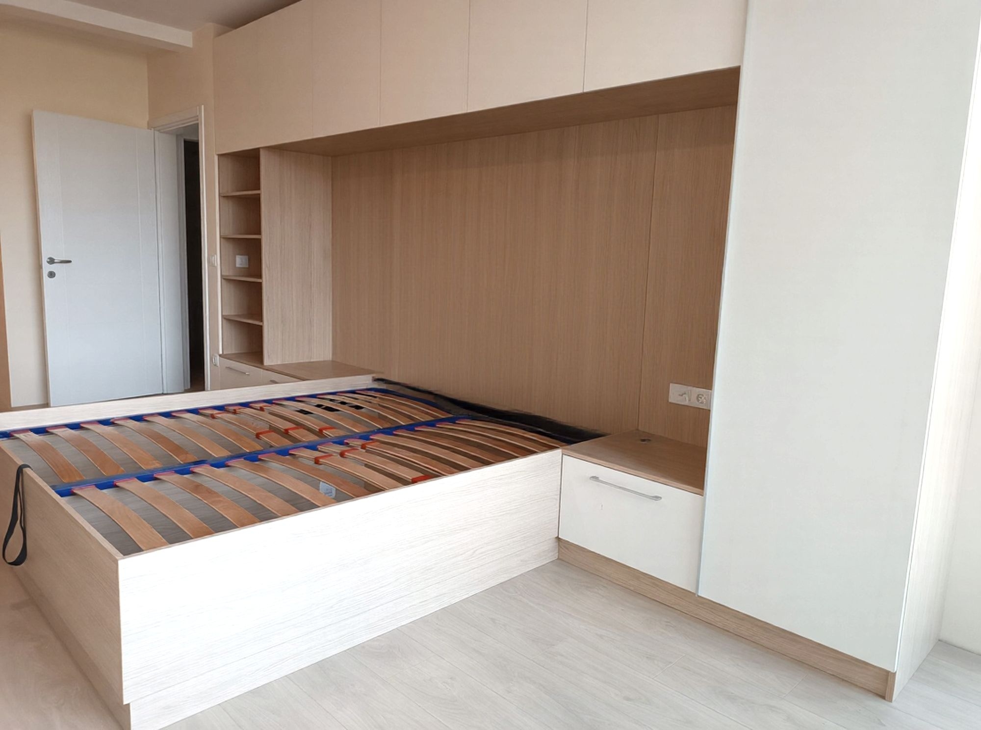 Легло с повдигащ механизъм и табла с интегрирани нощни шкафчета в дървесен декор.