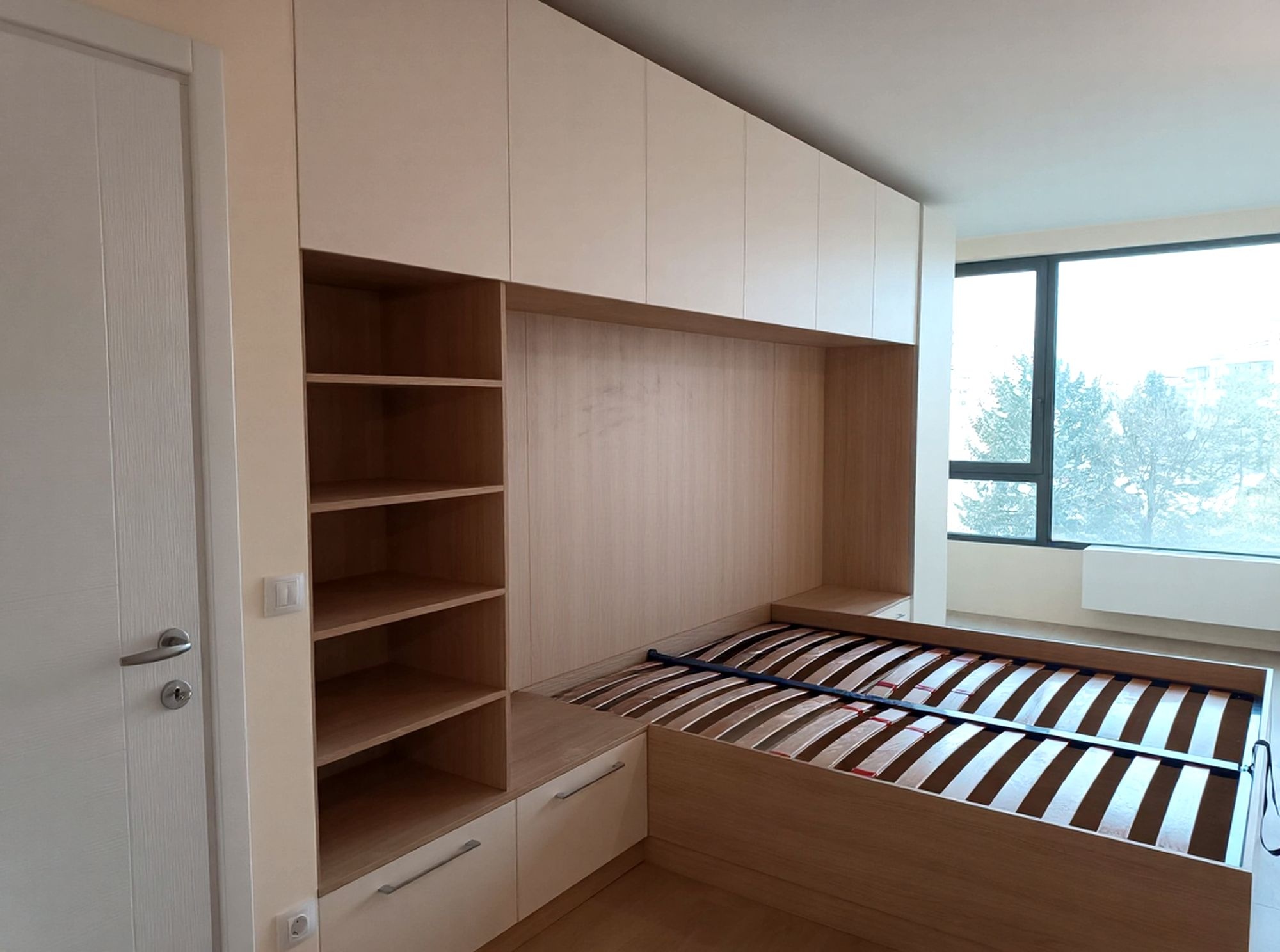Композиция около леглото с дълбоки горни шкафове и странични рафтове за книги.