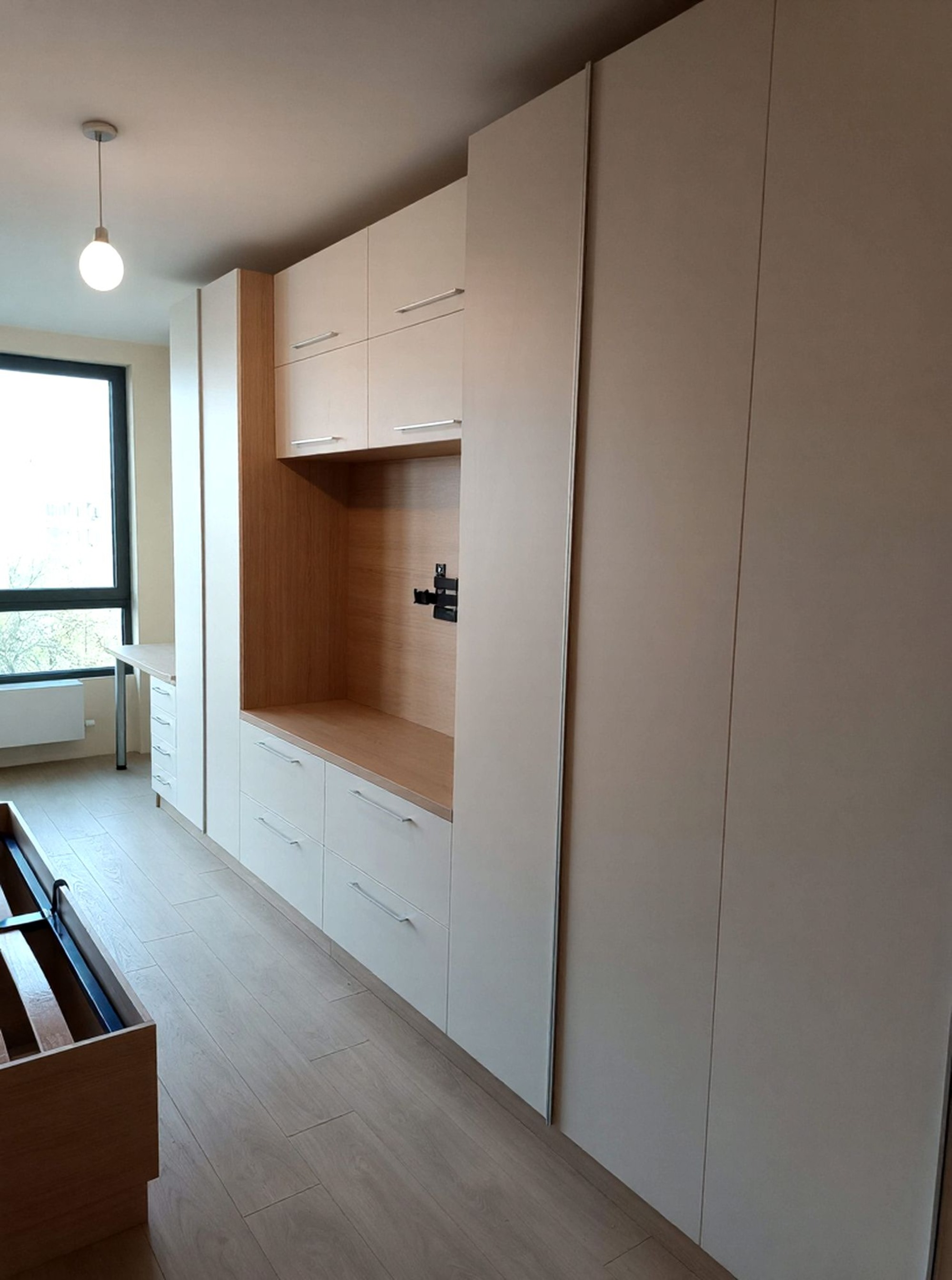 Гардеробна стена с високи врати и зона за телевизор с долни шкафове.