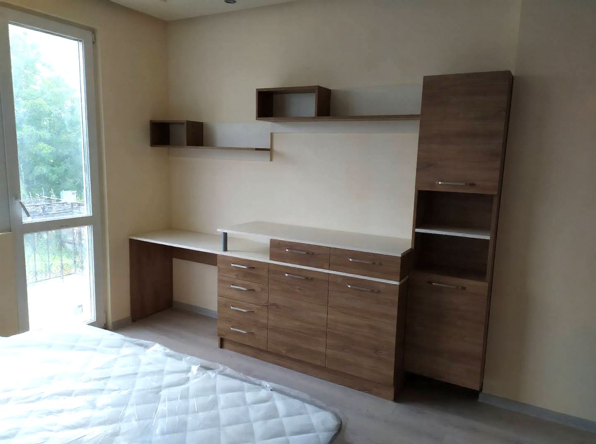 Работен кът с бюро и скрин в дървесен декор H1113 ST10, окачени етажерки и плавни хоризонтални линии.