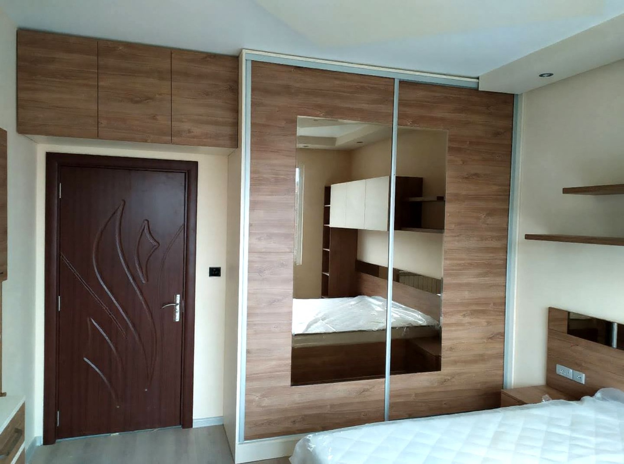 Гардероб с плъзгащи врати и огледален модул, отразяващ цялата мебелна композиция.