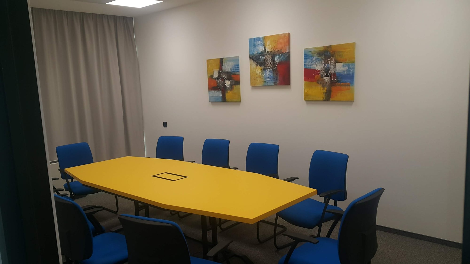 Ъглова модерна кухня по поръчка със светли гланцови шкафове, плот светъл дъб, черни дръжки и LED осветление.