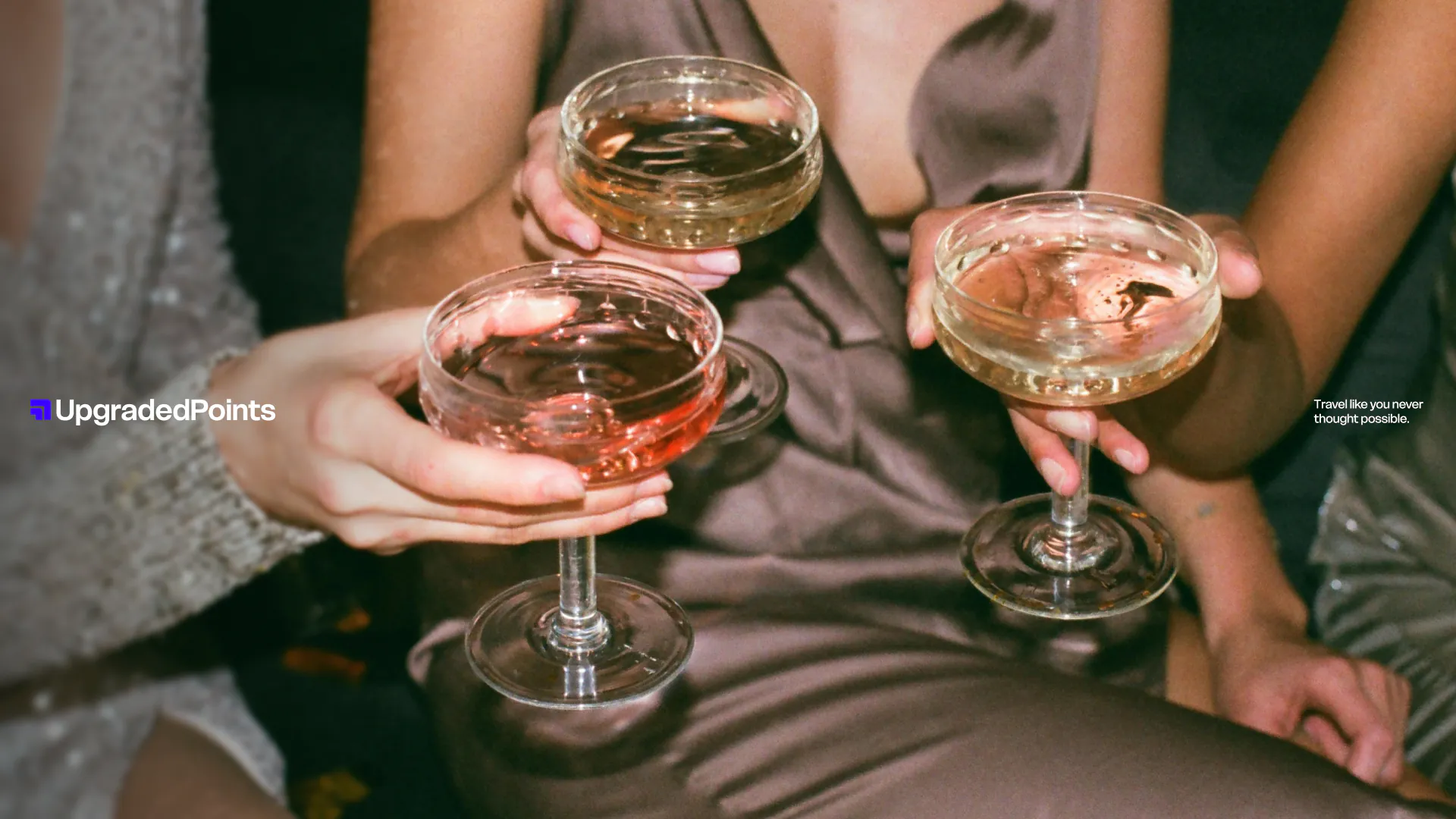 Three people holding champagne glasses filled with sparkling wine for a toast.