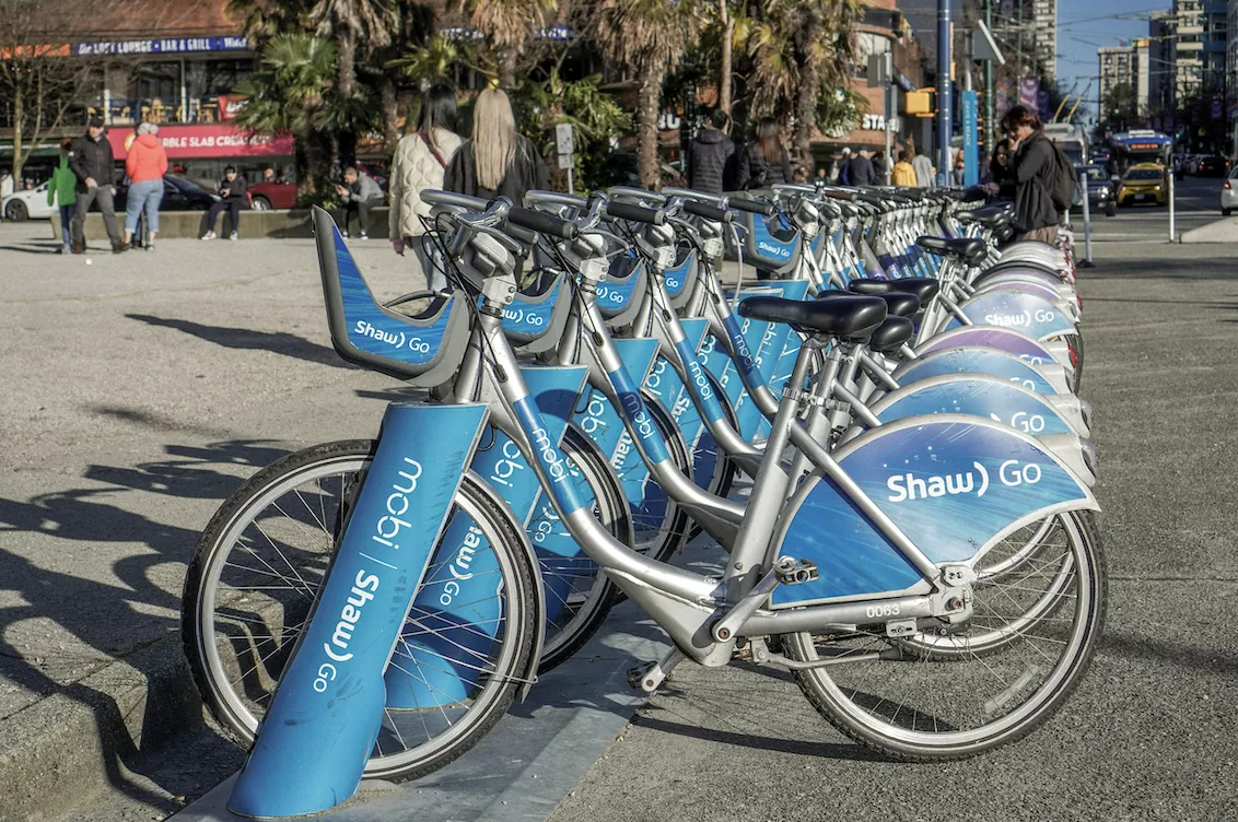 A row of blue bicycles parked next to each other