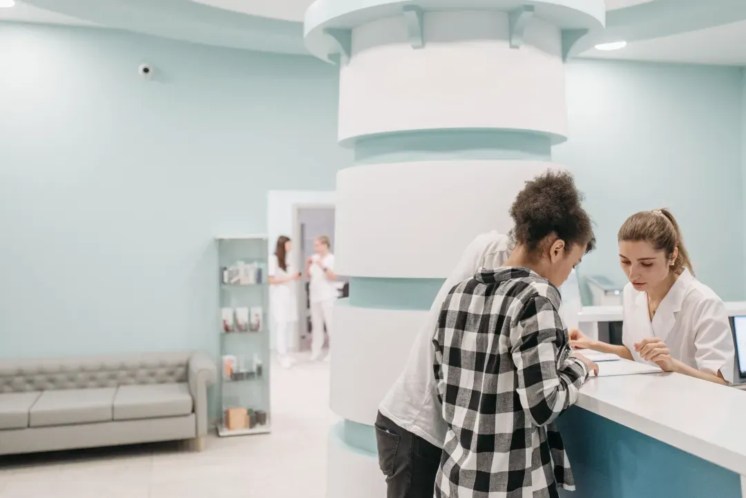 Healthcare professionals assisting at a modern clinic reception desk.