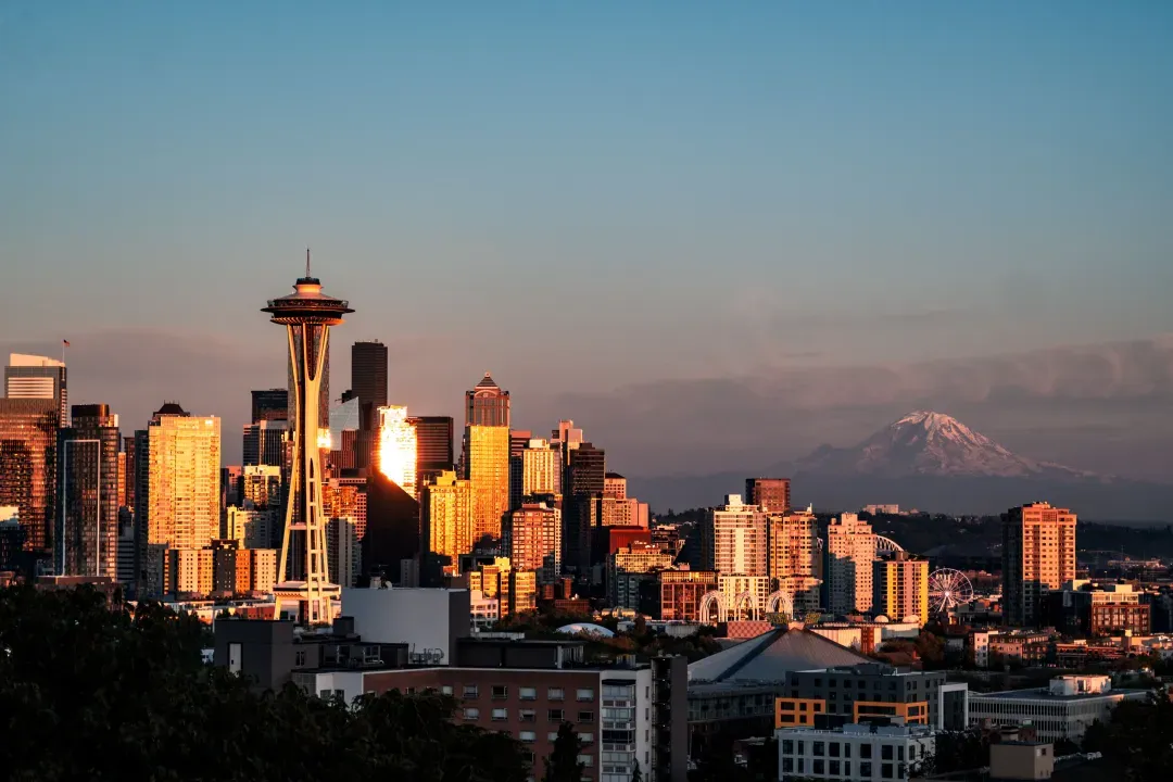 Stunning sunset view of Seattle skyline with Space Needle and Mount Rainier in the background.