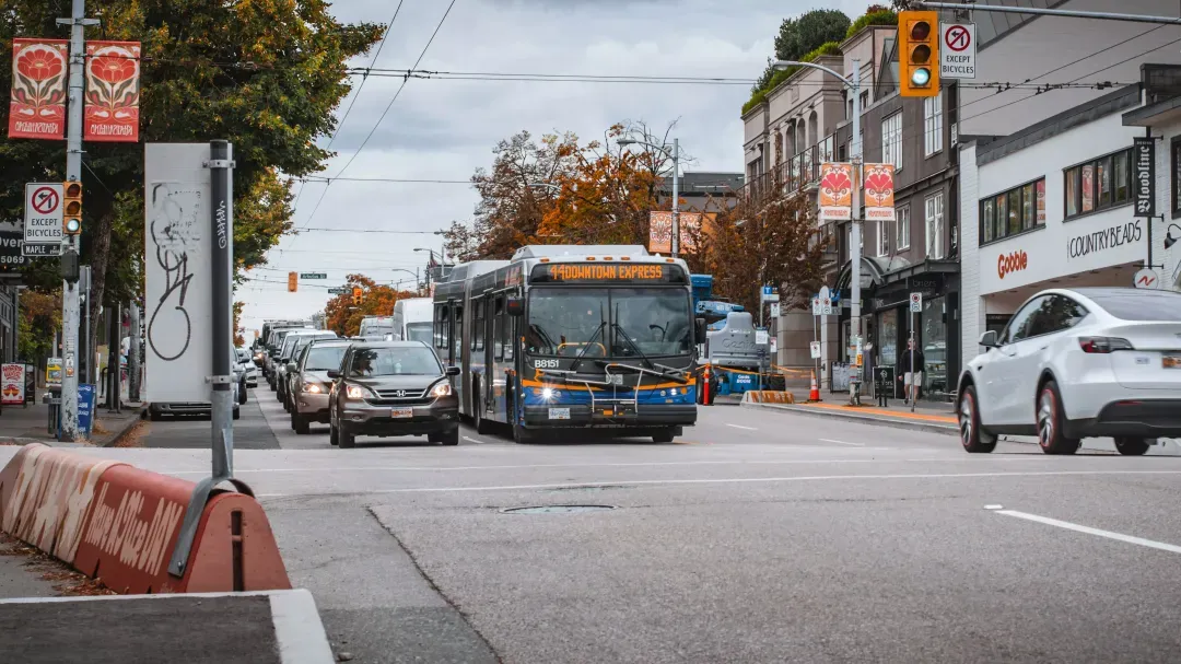 A city bus driving down a street next to tall buildings