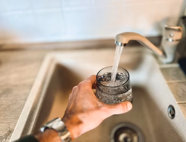 Clear tap water being poured into a glass for travel health and hydration guidance
