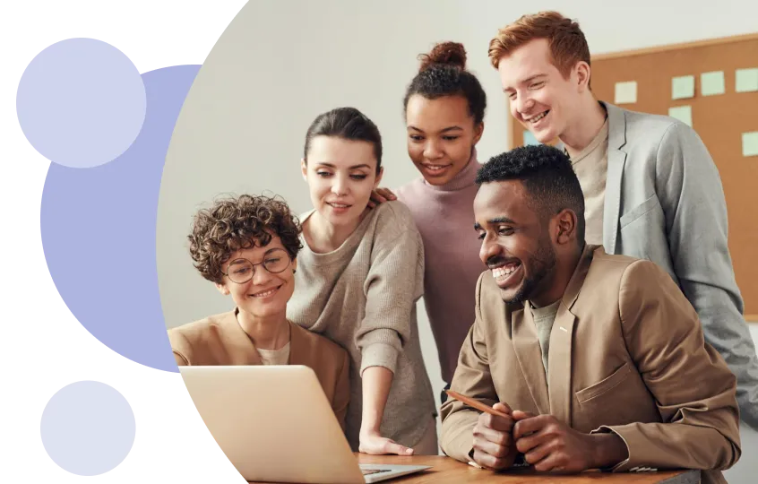 Grupo de cinco jóvenes profesionales de diferentes orígenes sonriendo y mirando juntos un ordenador portátil en una oficina.