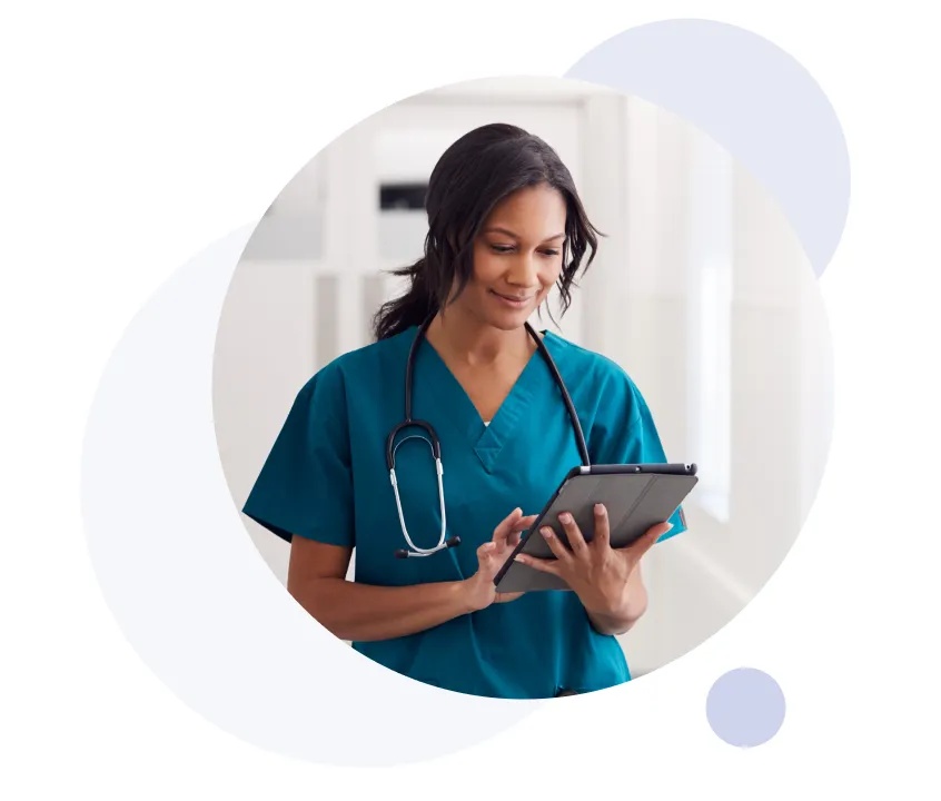 Mujer profesional de la salud con bata azul y un estetoscopio colgado al cuello utilizando una tableta digital.