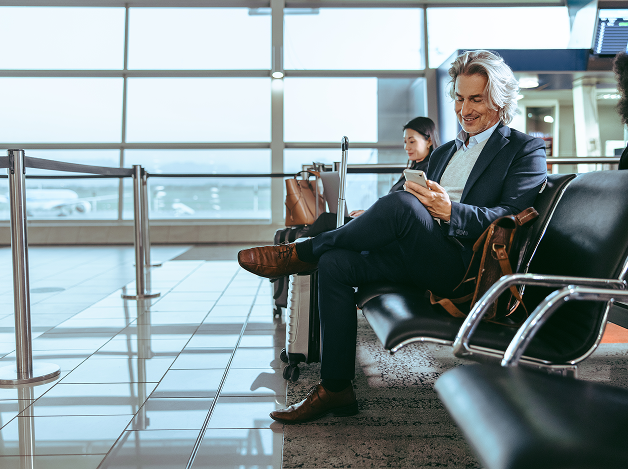 Businessman seated in an airport departure lounge using a smartphone