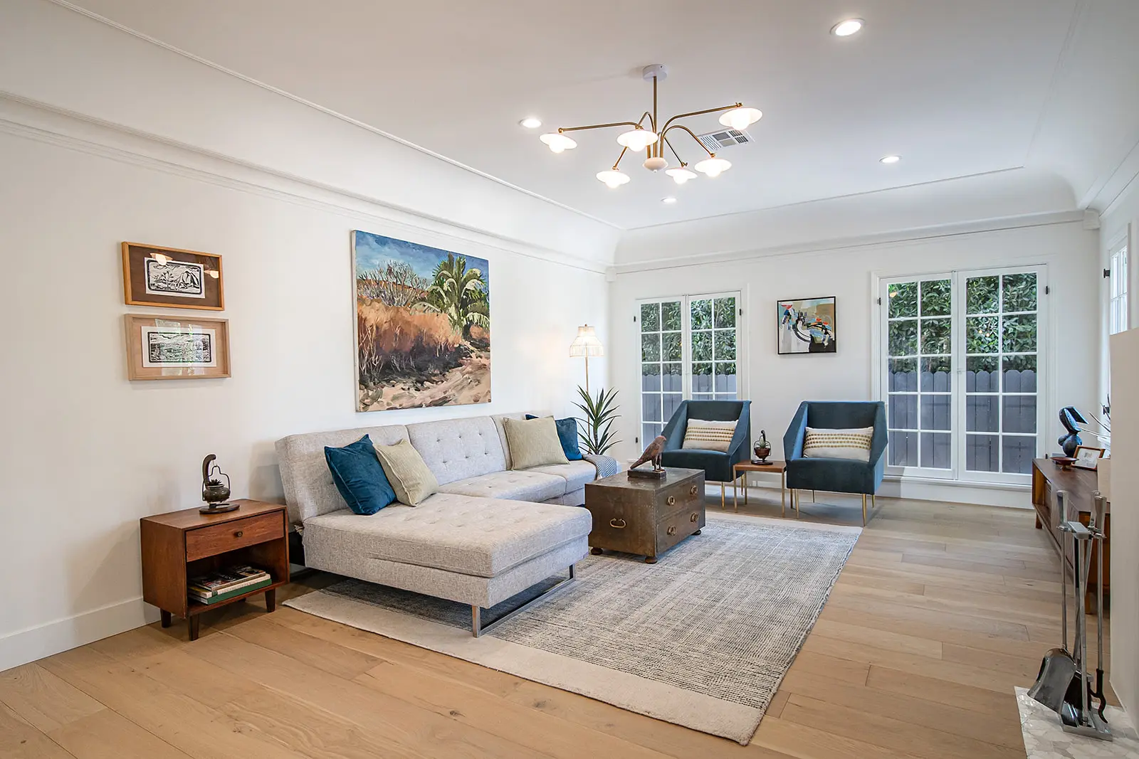 Expansive open-concept living area by Enhaus Design & Build, seamlessly connecting a luxury kitchen with a fluted oak island, a central dining space, and a living room centered around a green sectional sofa.