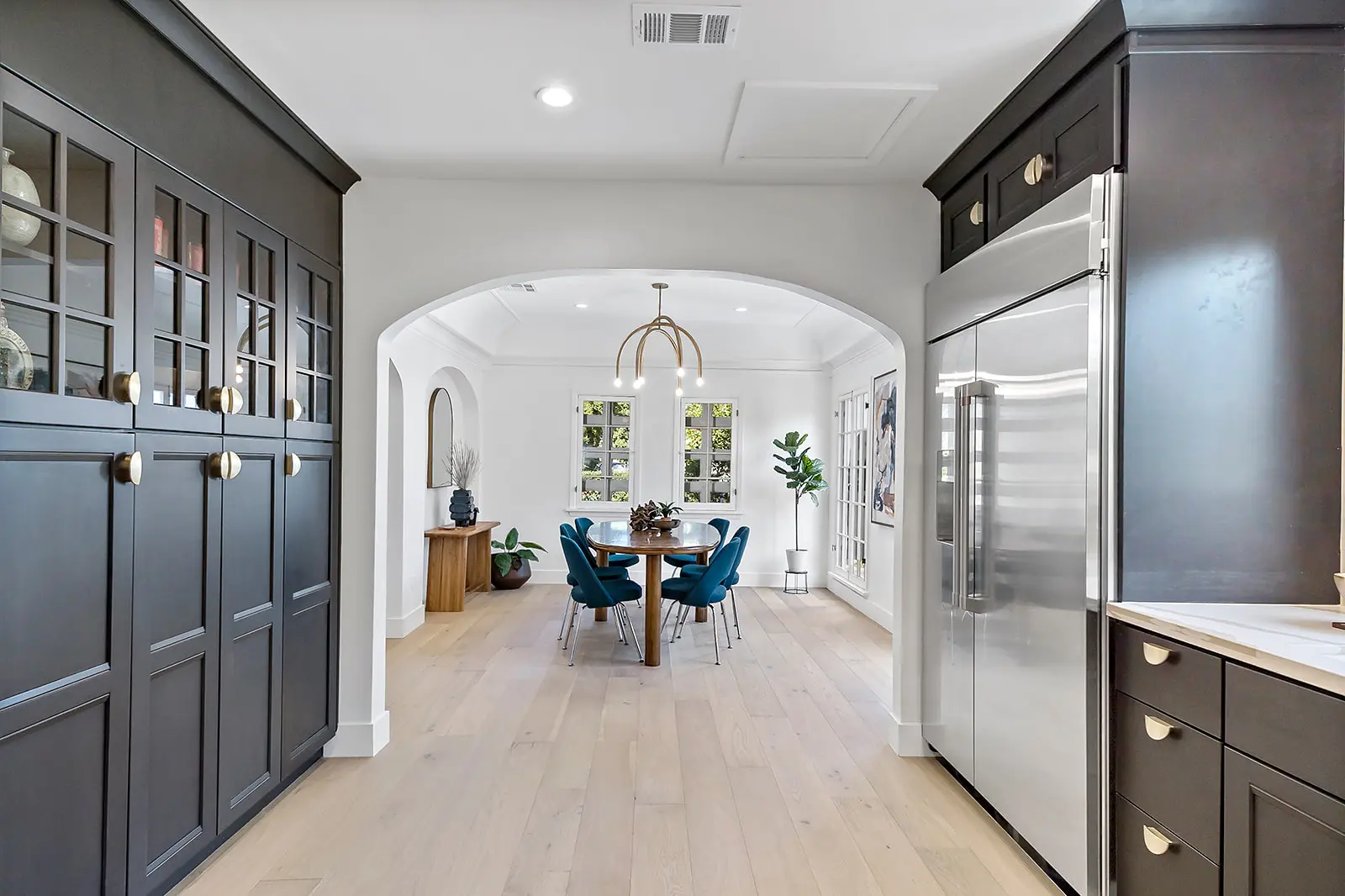 Enhaus master bathroom design showcasing a custom light oak door frame with an arched fluted glass insert, revealing a glimpse of warm terracotta tile inside.