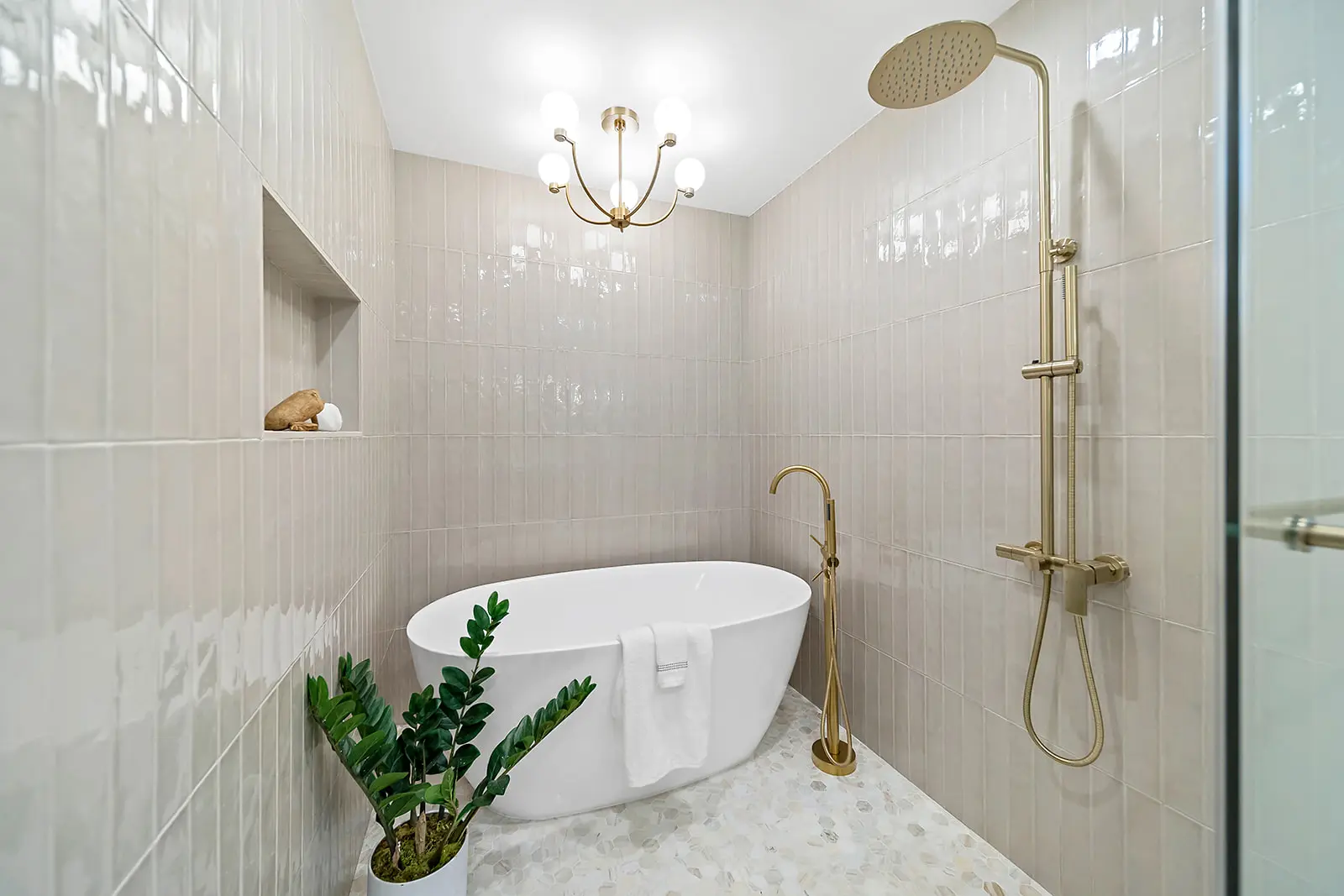 Luxury bathroom suite by Enhaus Design & Build, showing a seamless transition from a walk-in shower with vertical neutral tiles to a freestanding oval soaking tub.