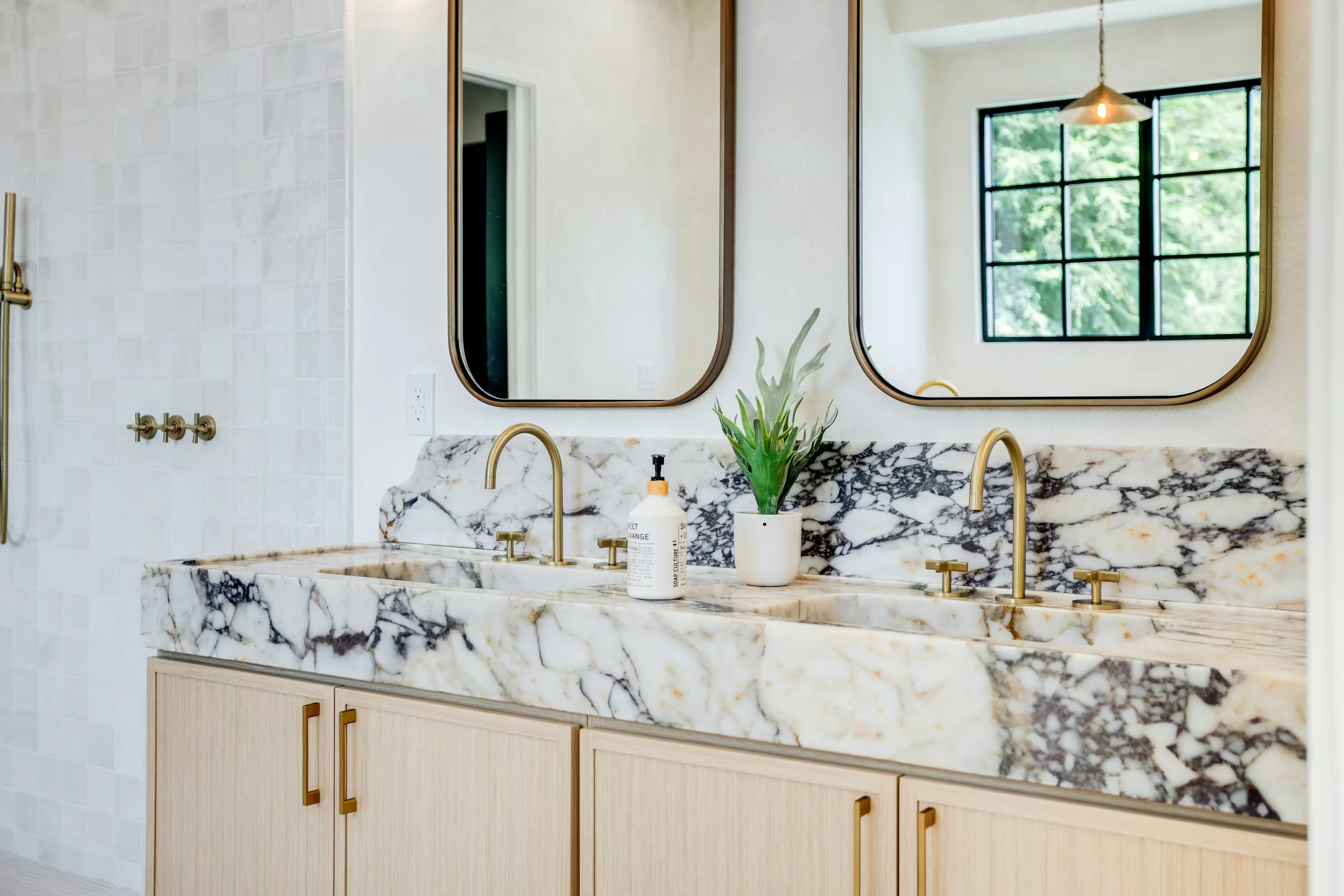 Expansive open-concept living area by Enhaus Design & Build, seamlessly connecting a luxury kitchen with a fluted oak island, a central dining space, and a living room centered around a green sectional sofa.