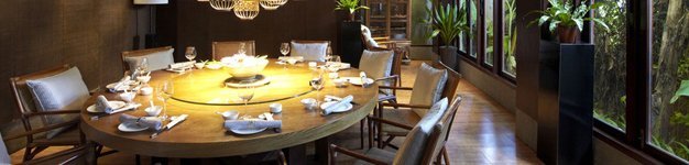 Elegant dining room with a large, round wooden table set for eight. 