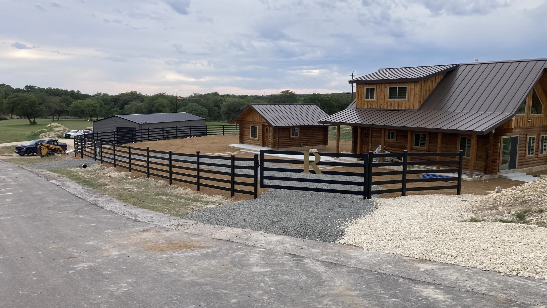 Finished custom five-rail fence and gate around a Texas Hill Country cabin
