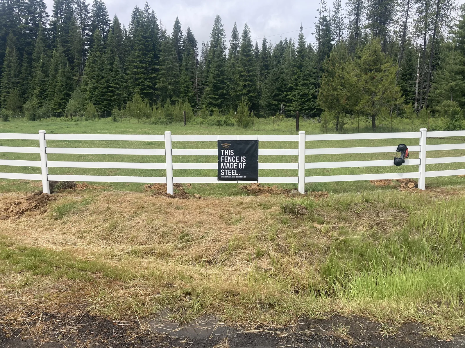 Roadside overview of white Buckley Steel Board fencing at the Clarkia, Idaho horse property