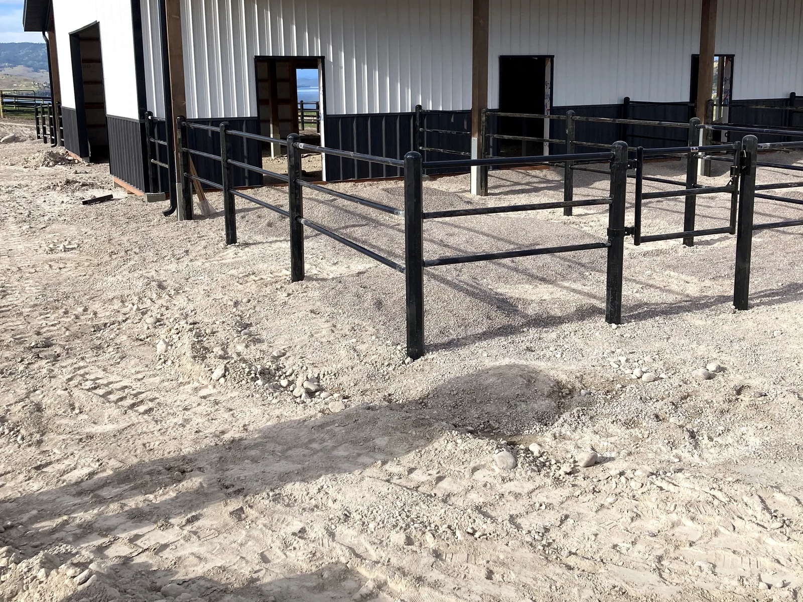 Side-angle view of black Priefert Estate Fence beside the Montana barn