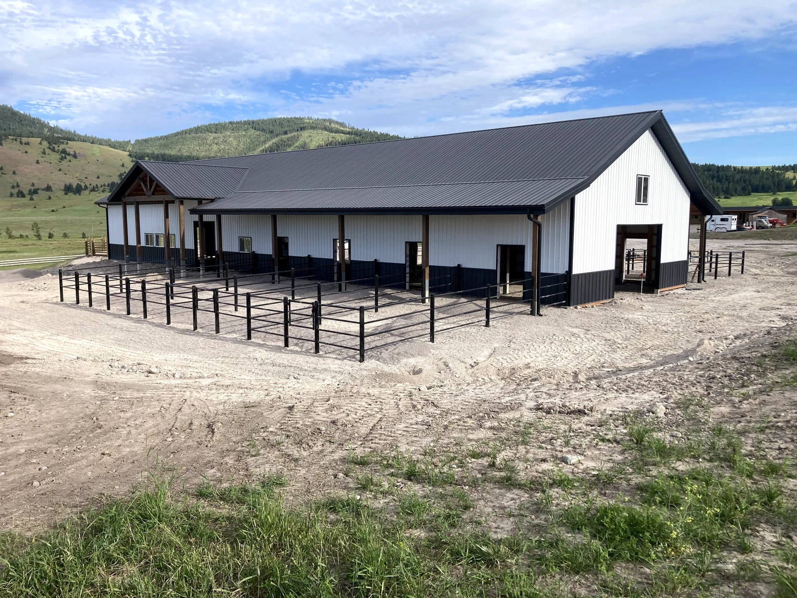 Wide view of black Priefert Estate Fence paddocks beside the barn in Big Arm, Montana