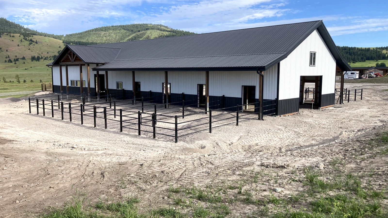 Wide view of the Montana Barn Paddocks with black Priefert Estate Fence and the barn