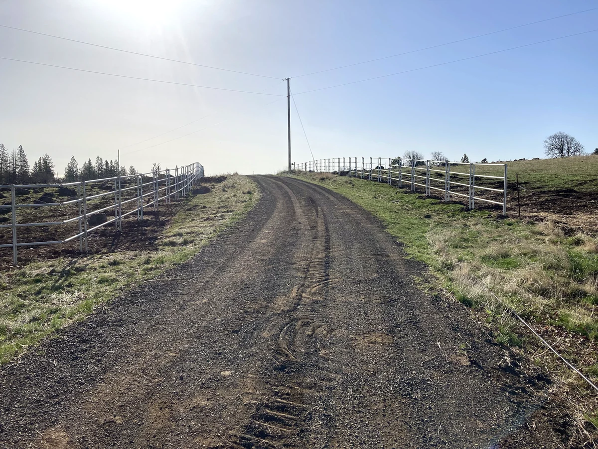 Four-rail Noble Contour fence lining both sides of the driveway at the Goldendale, Washington property