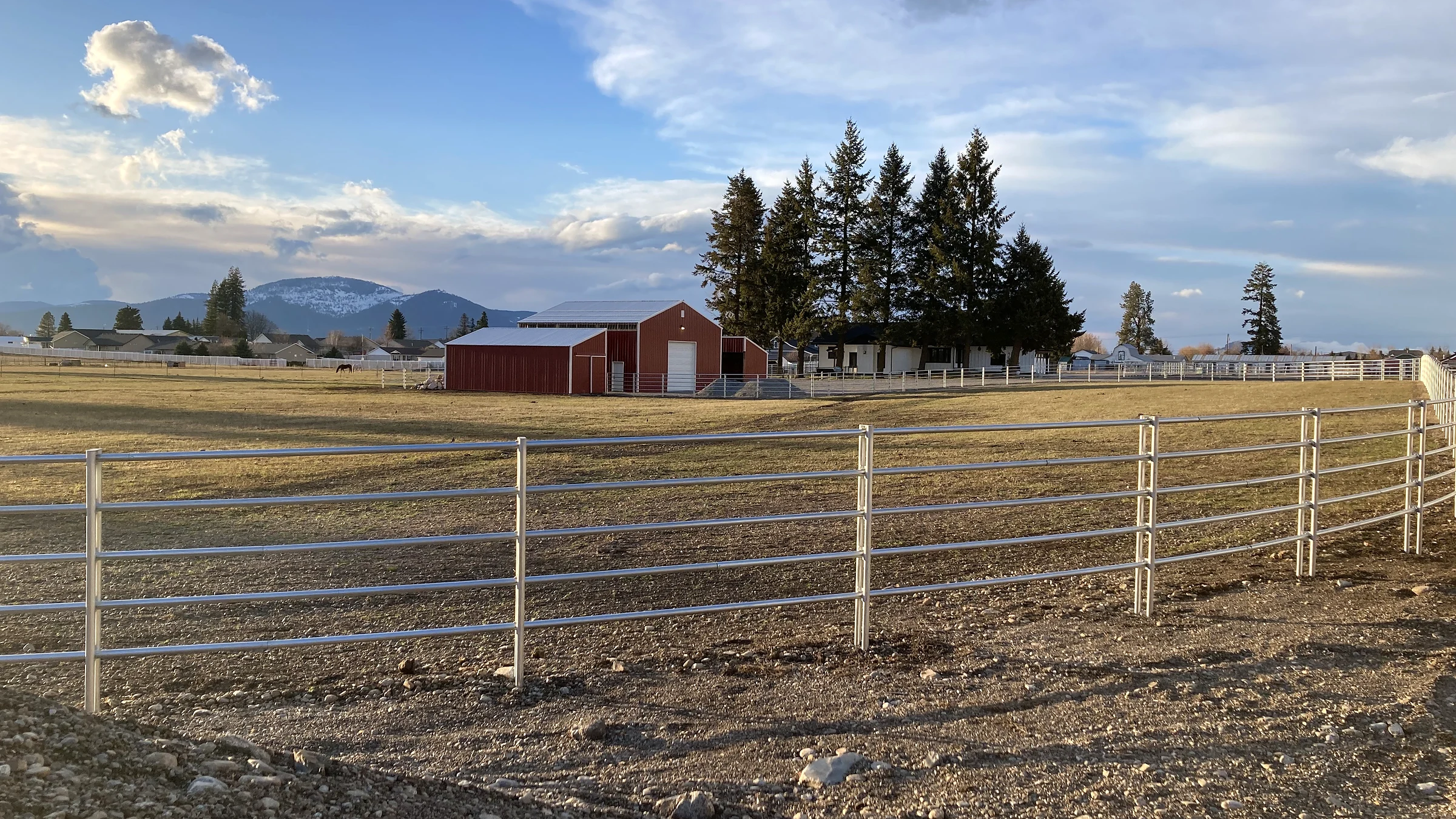 Noble Contour paddock fencing, barn, and mountain setting at the Lacey Avenue project in Hayden, Idaho