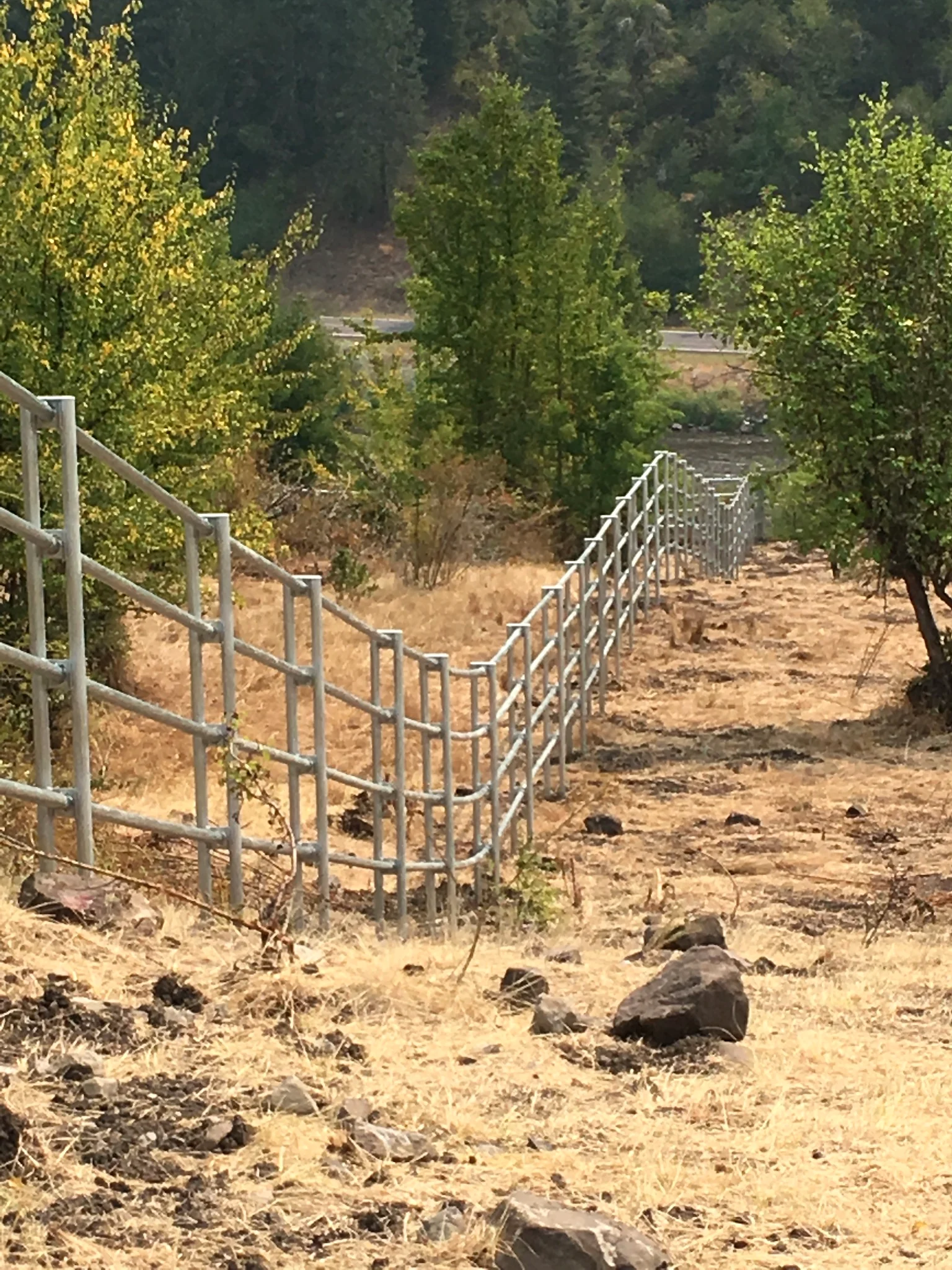 Closer downhill view of Noble Contour fence across rocky ranch terrain near Stites, Idaho