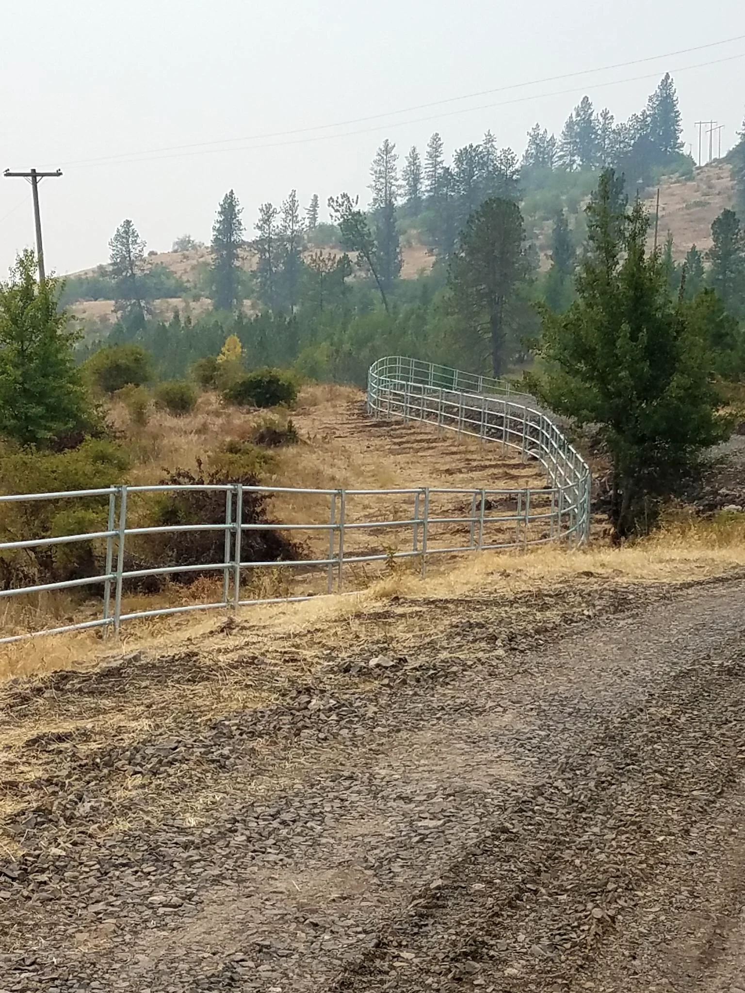 Curving Noble Contour fence beside the driveway on the rugged ranch near Stites, Idaho