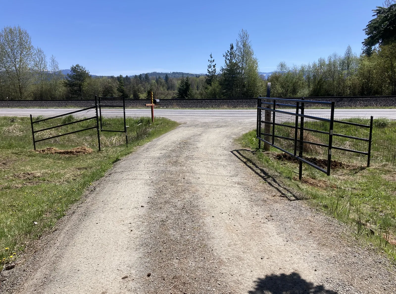 Black Frontier mesh fence and double gates framing the driveway at a North Idaho home.