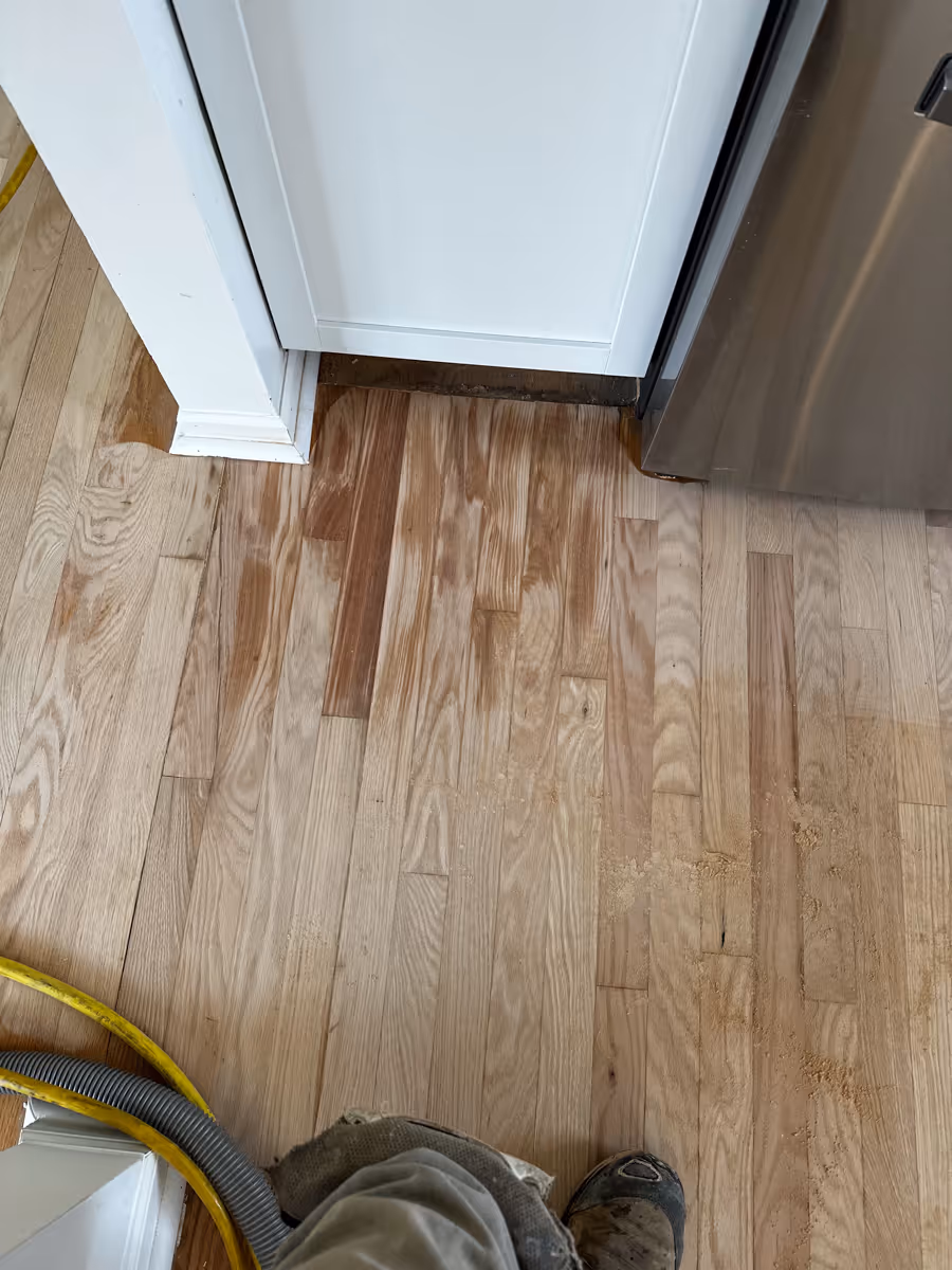 Water damaged hardwood floors near a dishwashing machine