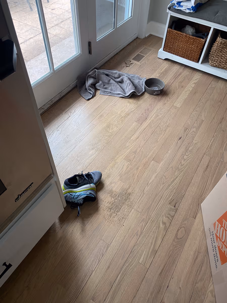 Water damaged hardwood floors near an entry way with dog water dish
