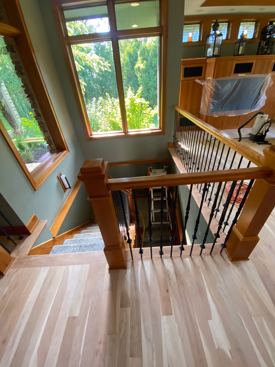 Hardwood floors at the top of a stair case with natural light from big windows