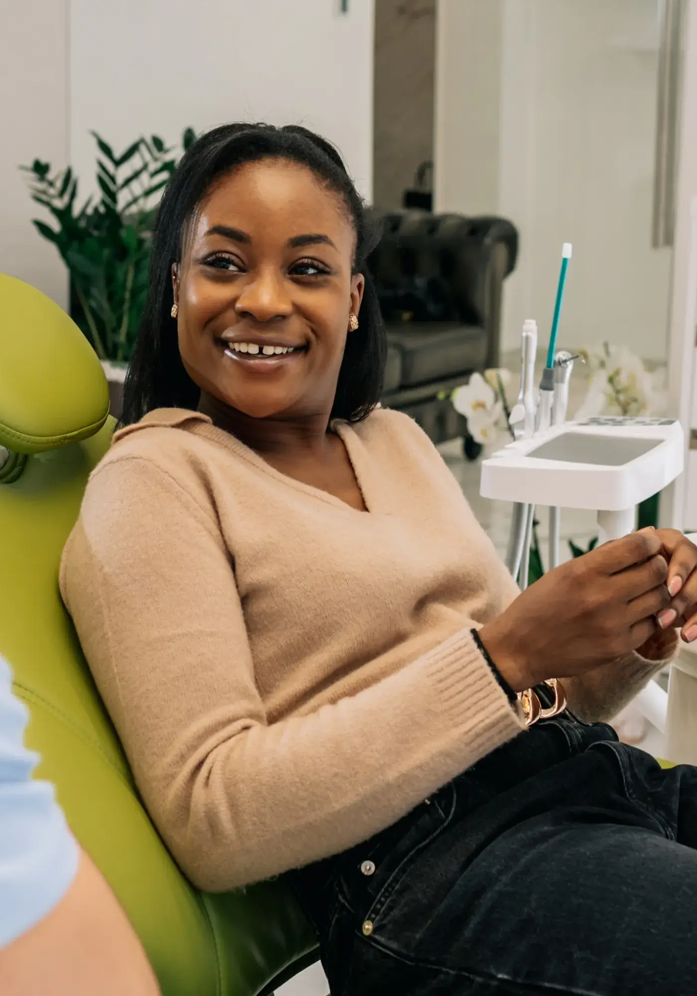 Smiling woman sitting in a green dental chair in a dental office.